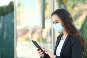 Woman wearing a protective mask using phone
